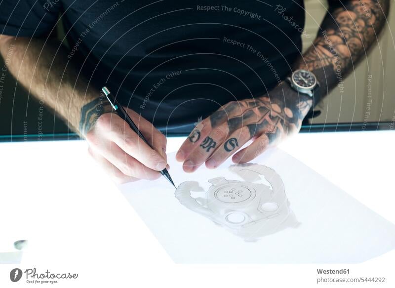 Tattoo artist designing motif on light table in studio man men males drawing sketching tattooist tattooer tattoos Adults grown-ups grownups adult people persons
