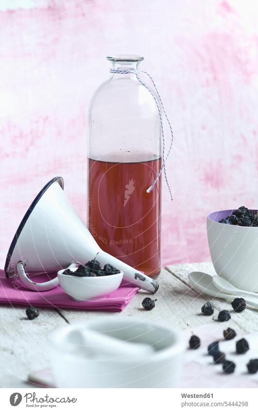Glass bottle of homemade sloe sirup, funnel and fruits Blackthorn sloes Prunus spinosa L. scattered nobody porcellain spoon fabric fabrics cloth string strings