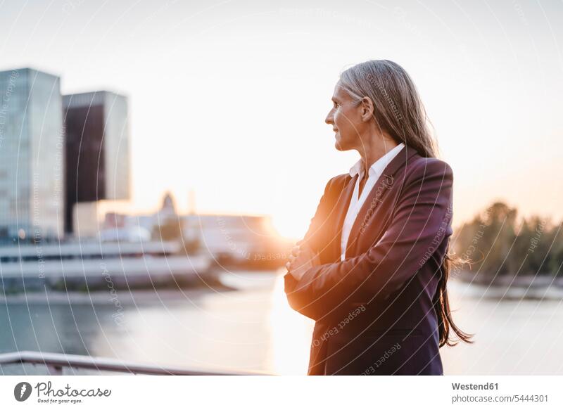 Confident businesswoman outdoors at sunset portrait portraits smiling smile standing businesswomen business woman business women business people businesspeople