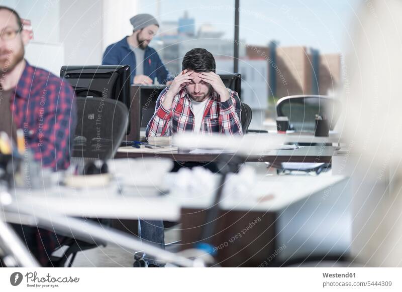 Man concentrating at desk in office thinking cogitate offices office room office rooms Concentration concentrated man men males workplace work place