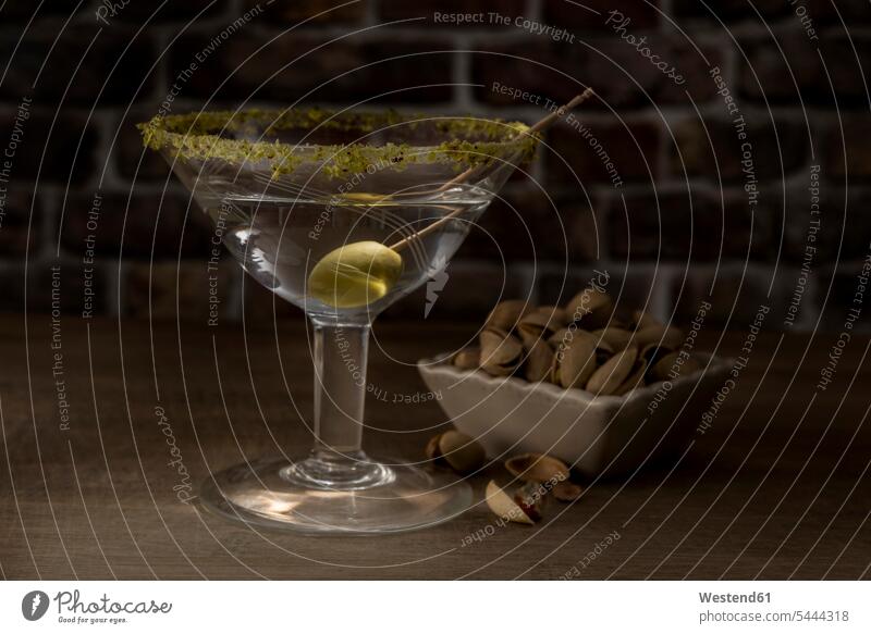Dry Martini with green olive and pistachio drinking enjoyment indulgence lifestyle life styles wooden garnished tooth pick Toothpick Toothpicks tooth picks