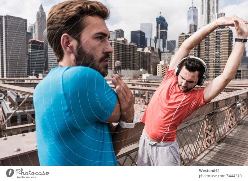 USA, New York City, two athletes stretching on Brooklyn Brige friends Jogging man men males bridge bridges friendship fitness sport sports Adults grown-ups