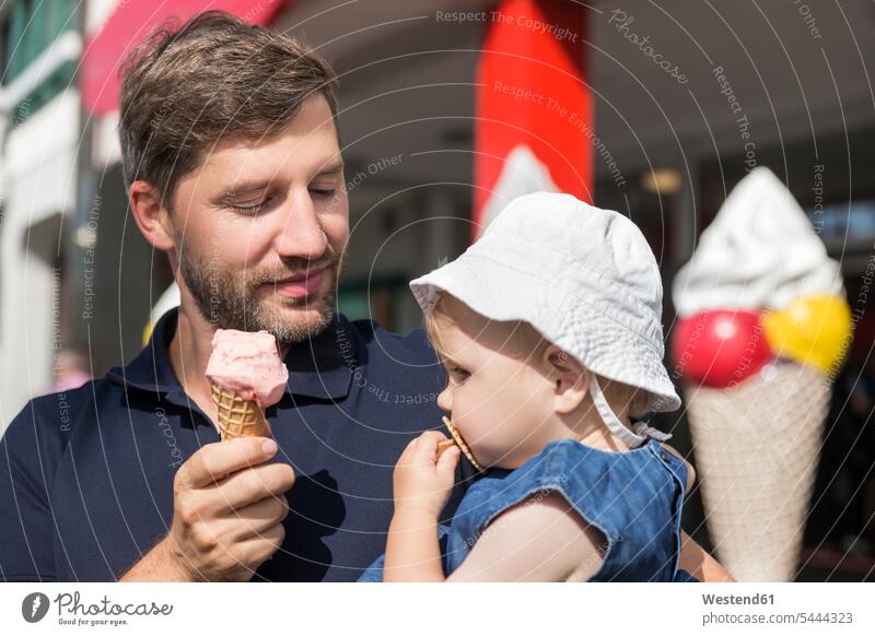 Father eating ice cream holding daughter daughters happiness happy looking eyeing family families father pa fathers daddy dads papa child children people