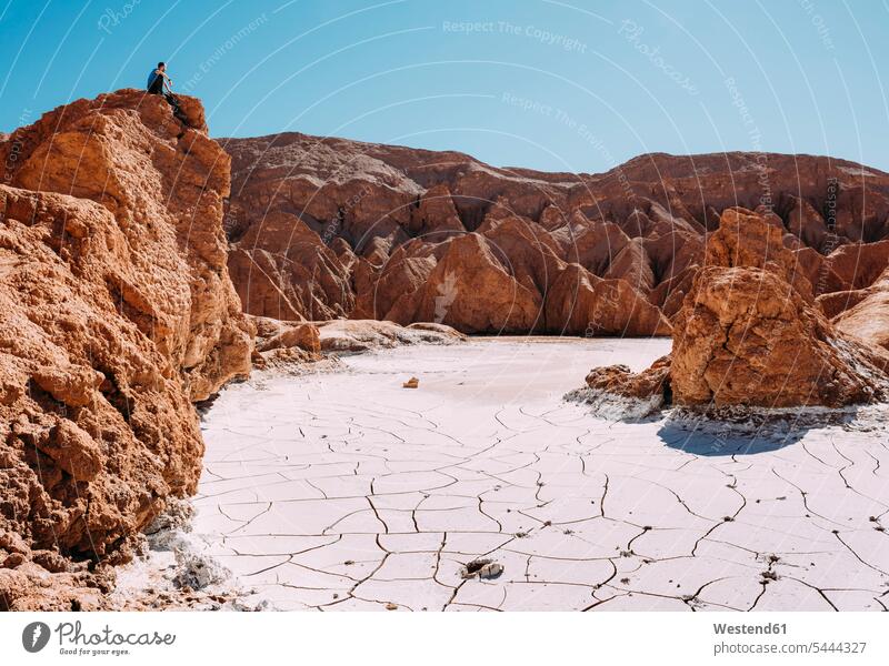 Chile, Atacama Desert, man sitting on a red rock looking at view watching men males desert Deserts seeing viewing Adults grown-ups grownups adult people persons