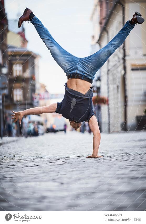 Man doing a handstand in the city man men males handstands Fun having fun funny Adults grown-ups grownups adult people persons human being humans human beings