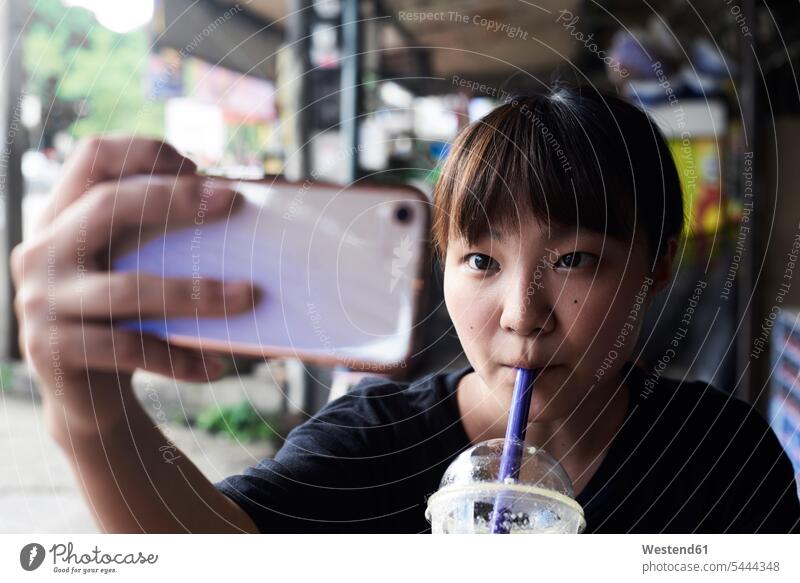 Portrait of woman drinking smoothie while taking selfie with smartphone portrait portraits Selfie Selfies females women Smartphone iPhone Smartphones Smoothies