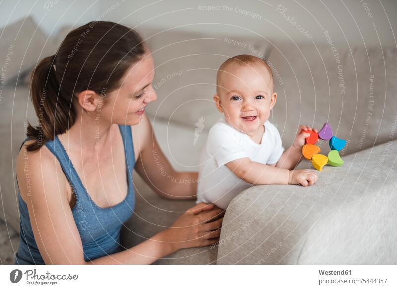 Happy baby girl with mother playing on couch mommy mothers ma mummy mama smiling smile infants nurselings babies parents family families people persons