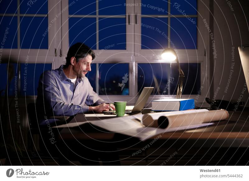 Man working late in office offices office room office rooms Businessman Business man Businessmen Business men males laptop Laptop Computers laptops notebook