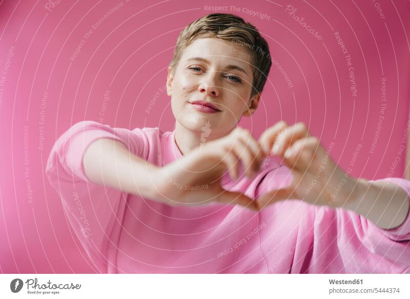 Portrait of woman in pink shaping heart with her hands Forming portrait portraits magenta hearts heart shapes human hand human hands females women colour