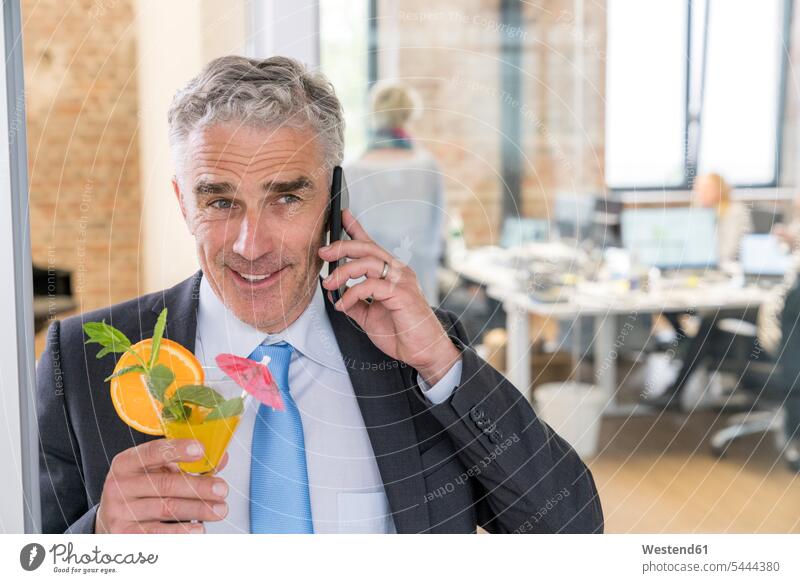 Mature businessman drinking cocktail while talking on the phone celebrating celebrate partying Cocktail Cocktails Long Drinks Businessman Business man
