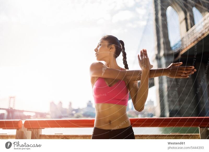 Woman doing stretching exercises in Manhattan near Brooklyn Bridge in the morning exercising training practising athlete sportswoman athletes female athlete