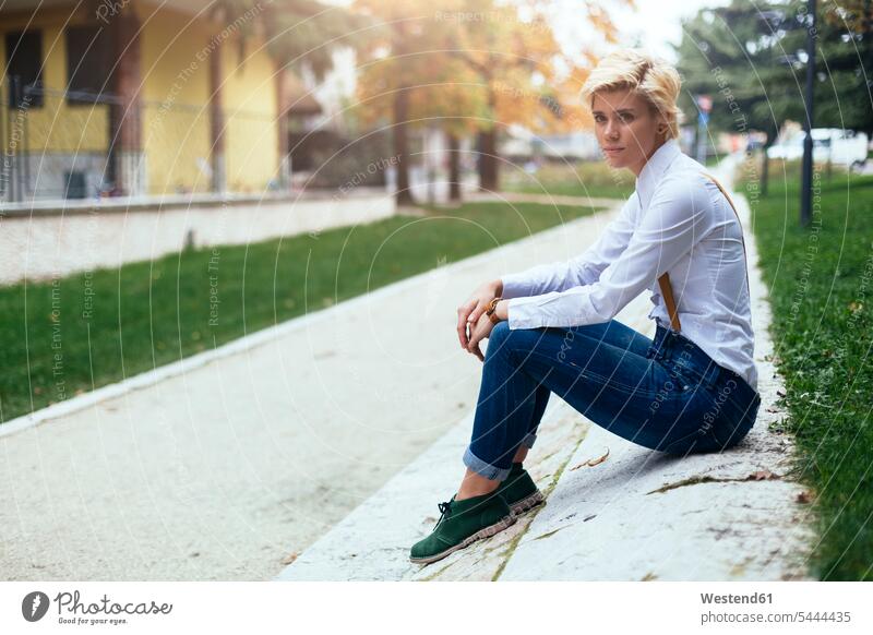 Sad teenage girl sitting at the roadside waiting Road Side hip trendy Seated blond blond hair blonde hair sad Teenage Girls female teenagers streets people