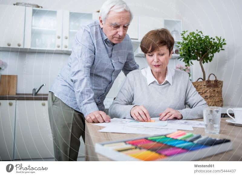 senior woman painting with crayons, husband watching drawing sketching hobby hobbies senior adults seniors old together looking looking at senior women