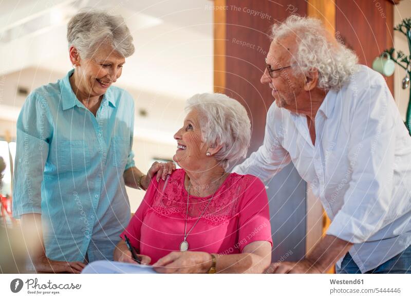 Senior woman signing a contract, friends reassuring her friendship retirement home nursing home form forms filling in fill in signature contracts senior women