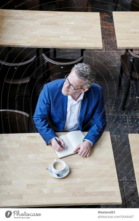 Mature businessman in cafe writing in diary Businessman Business man Businessmen Business men working At Work schedule timetable business people businesspeople