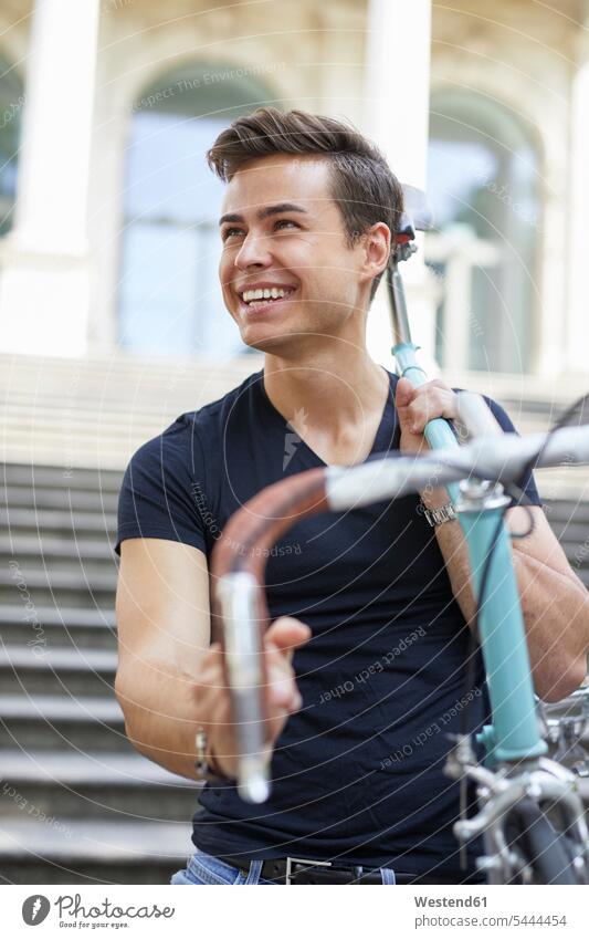 Portrait of happy young man with racing cycle on his shoulder portrait portraits men males bicycle bikes bicycles Adults grown-ups grownups adult people persons