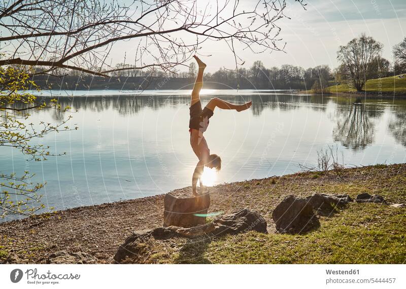 Germany, Bavaria, Feldkirchen, man doing a handstand at lakeshore handstands men males Parcour water waters body of water Adults grown-ups grownups adult people