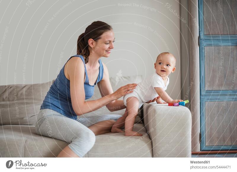 Happy baby girl with mother playing on couch settee sofa sofas couches settees smiling smile infants nurselings babies mommy mothers ma mummy mama people