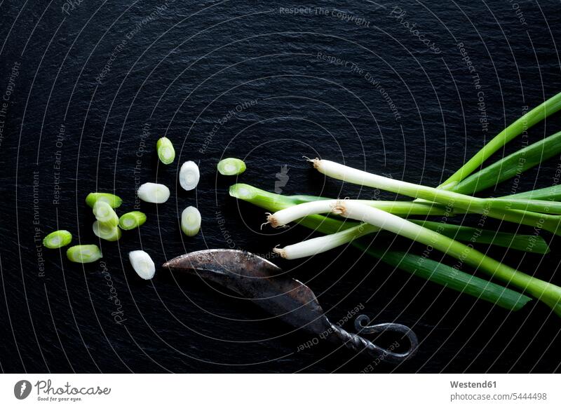 Whole and sliced spring onions and an old knife on slate overhead view from above top view Overhead Overhead Shot View From Above still life still-lifes
