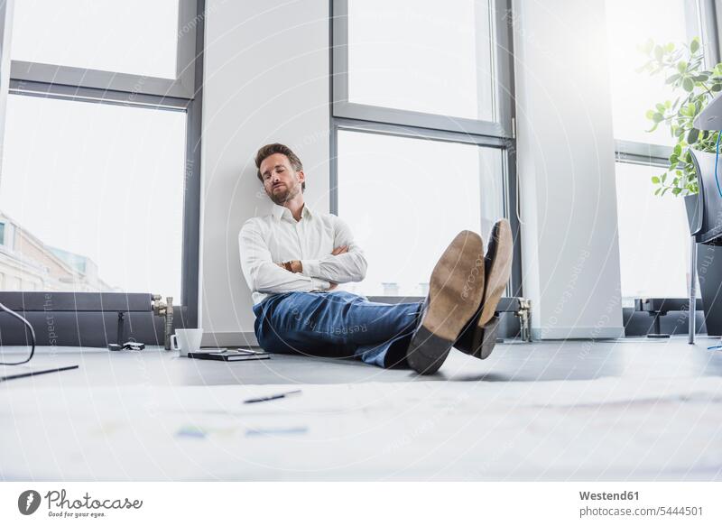 Businessman relaxing on the floor of his office offices office room office rooms Floor Floors workplace work place place of work floors sitting Seated architect