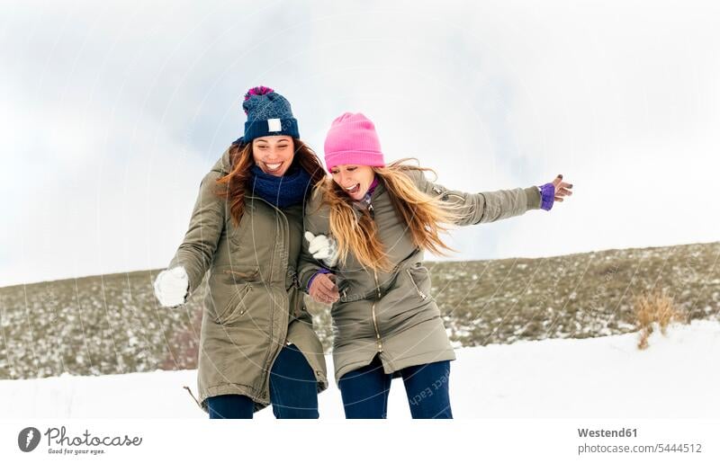 Two friends having fun in the snow female friends laughing Laughter winter hibernal friendship mate weather positive Emotion Feeling Feelings Sentiments