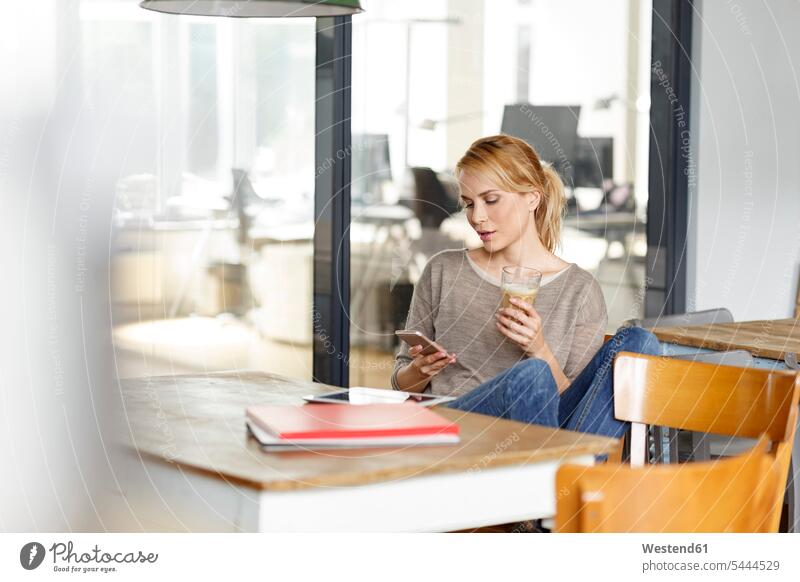 Woman checking cell phone in office mobile phone mobiles mobile phones Cellphone cell phones offices office room office rooms woman females women telephones