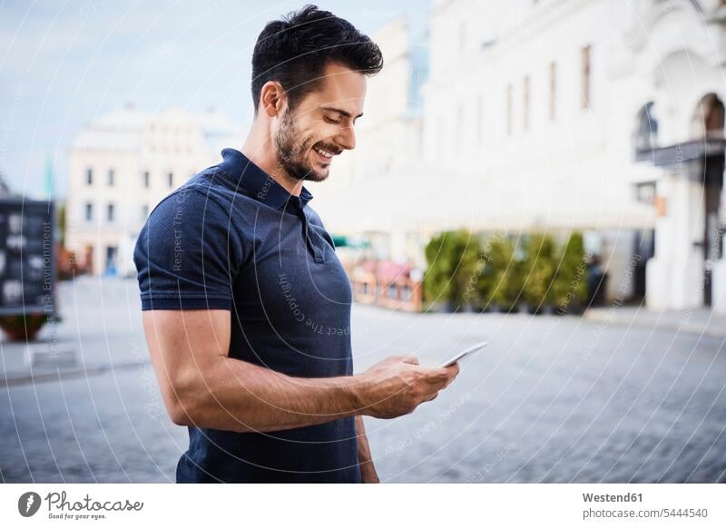 Smiling man using cell phone in the city happiness happy men males mobile phone mobiles mobile phones Cellphone cell phones smiling smile Adults grown-ups