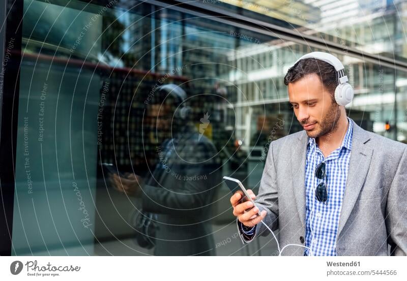 Businessman listening to music with headphones in the city headset Business man Businessmen Business men mobile phone mobiles mobile phones Cellphone cell phone