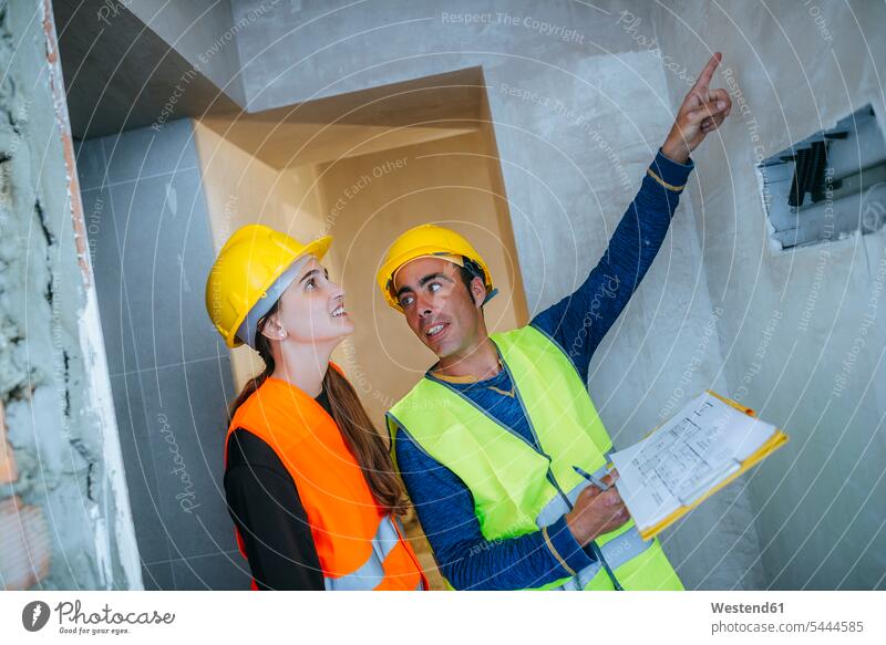 Construction worker showing electrical installation to woman construction plan building plan architectural drawing pointing point at pointing at