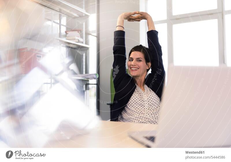 Happy businesswoman sitting in office, looking at laptop, stretching happiness happy Seated Laptop Computers laptops notebook smiling smile businesswomen