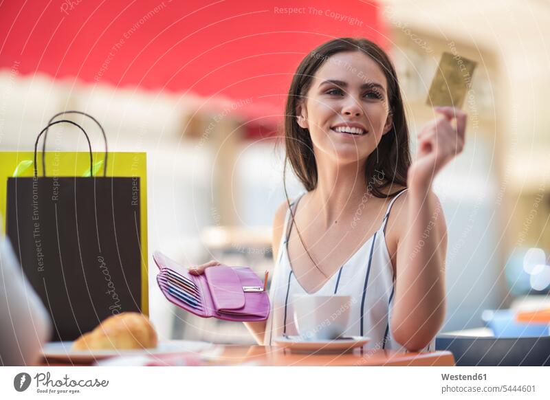 Smiling woman paying with credit card at cafe shopping bag shopping-bag shopping-bags shopping bags females women smiling smile debit card Adults grown-ups