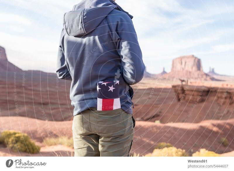 USA, Utah, back view of young man with folded American flag in his pocket at Monument Valley ensign national flags ensigns banner banners Stars And Stripes