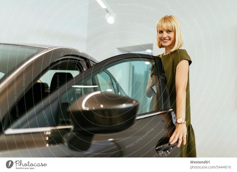 Blond woman choosing new car in car dealership female customer females women automobile Auto cars motorcars Automobiles select choose selecting car dealerships