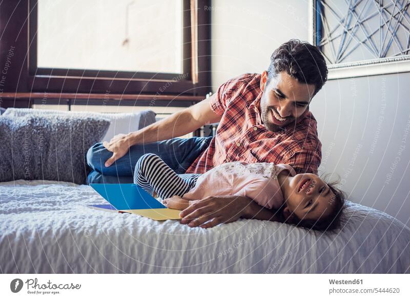 Father and daughter playing on bed father pa fathers daddy dads papa hugging cuddling beds together daughters parents family families people persons human being