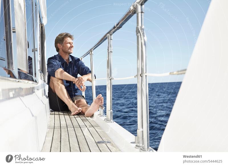 Content mature man sitting on his motor yacht men males motor yachts Adults grown-ups grownups adult people persons human being humans human beings Yacht Yachts