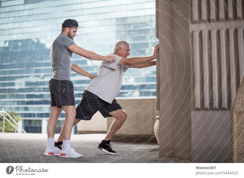 Fitness instructor guiding senior man doing a stretching exercise coach coaches trainer athlete Sportspeople Sportsman Sportsperson athletes Sportsmen