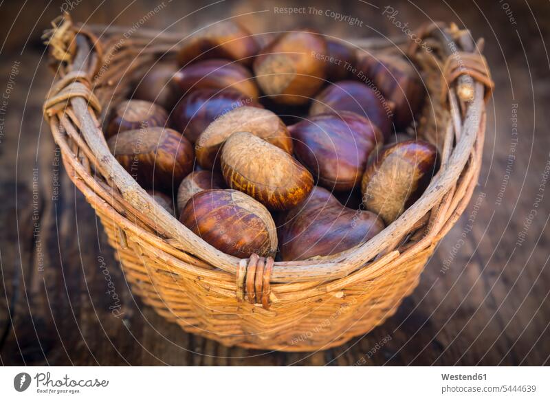 Roasted sweet chestnuts in a basket nobody dark large group of objects many objects copy space wooden collecting collected Chestnut Chestnuts