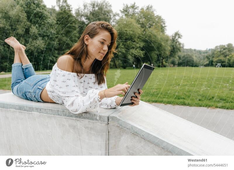 Young woman using lying in a skatepark using a tablet Skateboard Park skate park females women laying down lie lying down use digitizer Tablet Computer