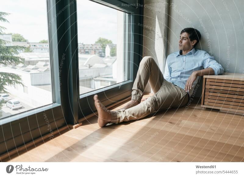 Man sitting on the floor looking out of window windows man men males Adults grown-ups grownups adult people persons human being humans human beings loft lofts