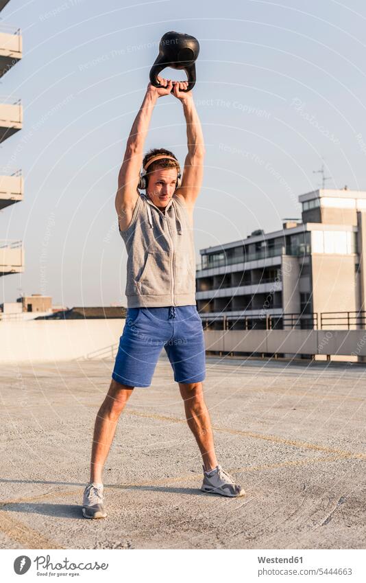 Young man exercising with kettle bell on a rooftop young fit weight weights Kettlebell Kettle bells Kettlebells Strength strong Force Strengthy Power training