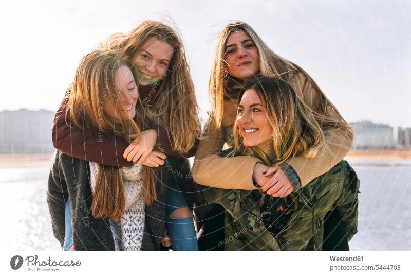 Four friends having fun together mate female friend pickaback Piggy Back piggy-back Piggybacking portraits smile ocean human human being human beings humans