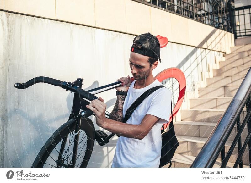 Young man carrying fixie bike downstairs bicycle bikes bicycles men males Adults grown-ups grownups adult people persons human being humans human beings