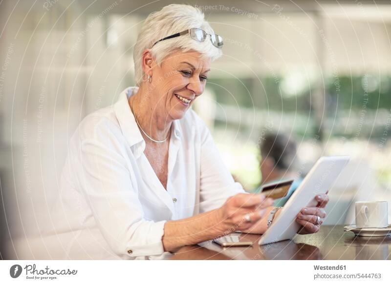 Senior woman shopping online with credit card smiling smile debit card senior women elder women elder woman old senior woman cashless banking finances financial