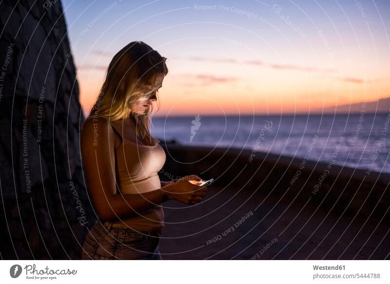 Woman using cell phone at sunset Smartphone iPhone Smartphones use sea ocean woman females women sunsets sundown mobile phone mobiles mobile phones Cellphone