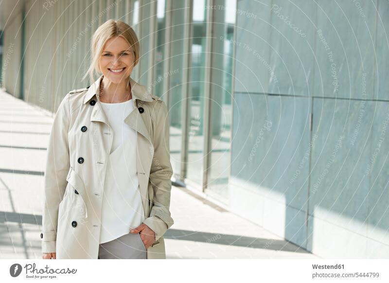Portrait of smiling blond woman wearing trench coat trenchcoat portrait portraits females women Adults grown-ups grownups adult people persons human being