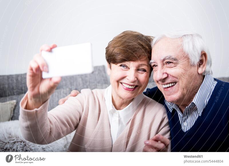 Senior couple sitting on couch, taking a smartphone selfie Germany Smartphone iPhone Smartphones self-portrait Self Portrait Photography Photographing Self