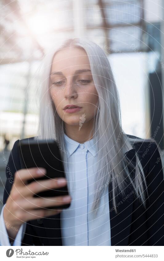 Young businesswoman checking cell phone in the city serious earnest Seriousness austere mobile phone mobiles mobile phones Cellphone cell phones businesswomen