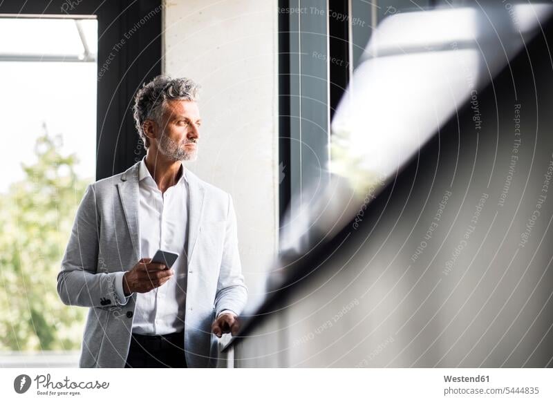 Mature businessman with cell phone looking out of window mobile phone mobiles mobile phones Cellphone cell phones windows Businessman Business man Businessmen