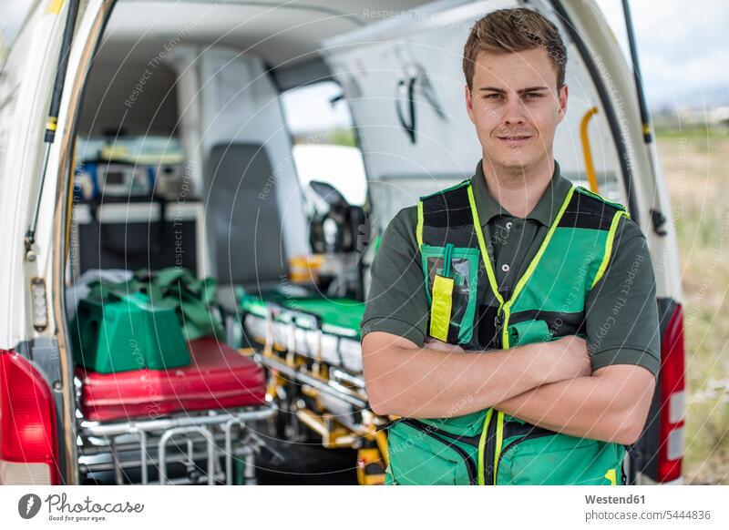 Paramedic standing with arms crossed in front of ambulance paramedic paramedics ambulance vehicles healthcare and medicine medical Healthcare And Medicines