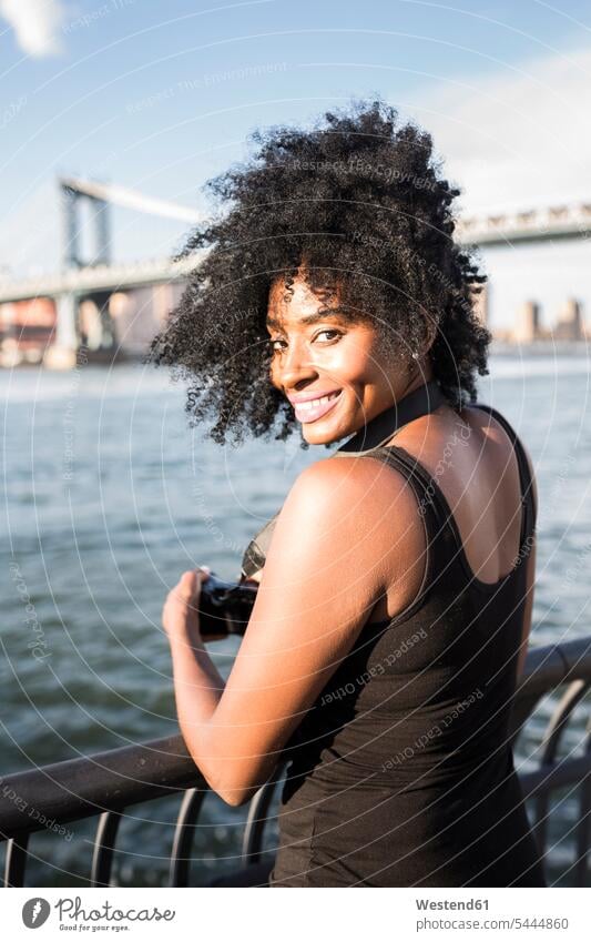 USA, New York City, Brooklyn, portrait of smiling woman standing at the waterfront River Rivers portraits bridge bridges females women smile waters